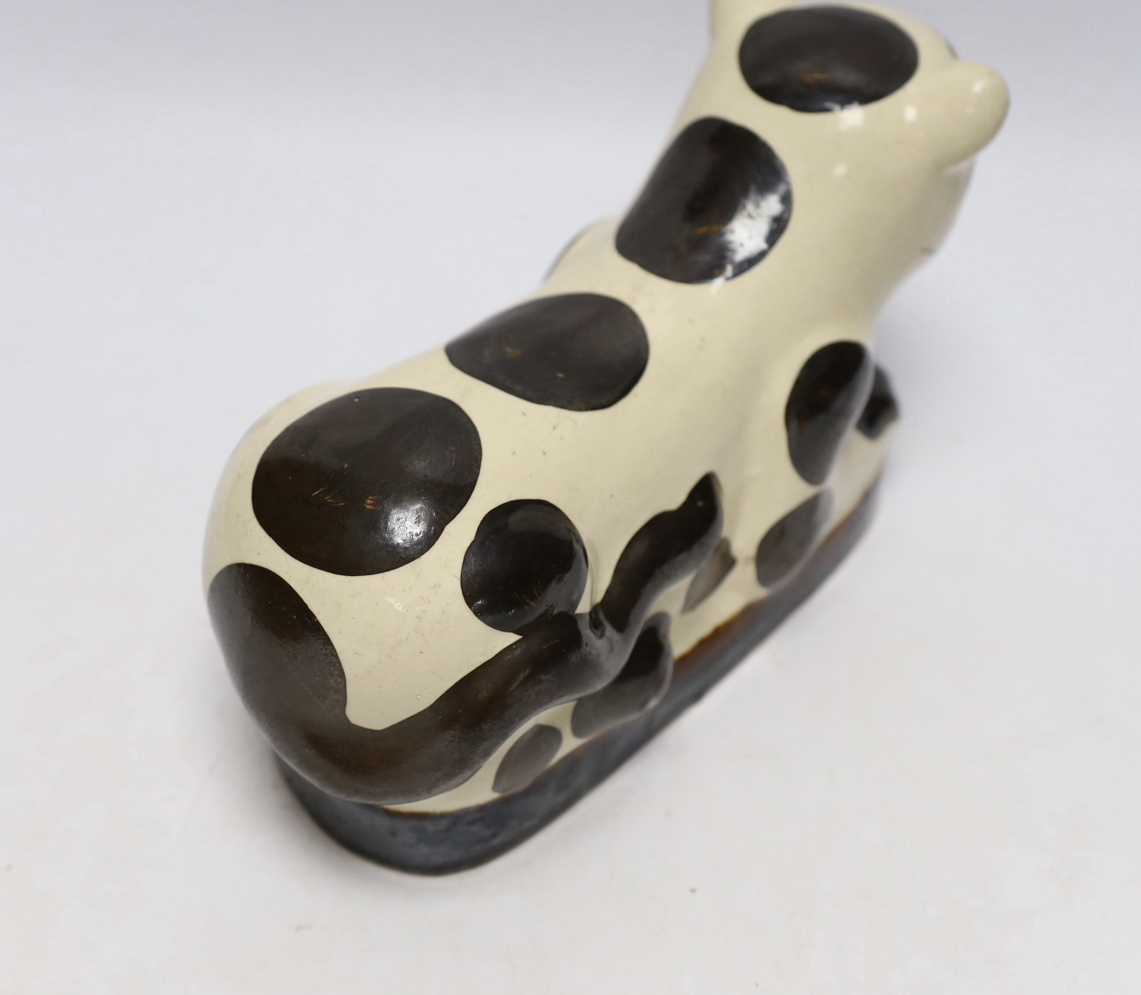A Chinese glazed earthenware cizhou style pillow headrest in the form of a black and white cat, 22cm